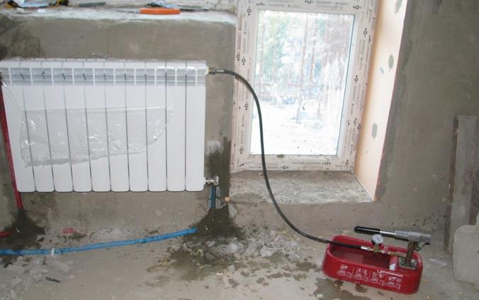 Фото: Опрессовка радиатора отопления с помощью специального прибора