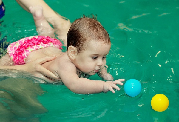 ребенок в бассейне играет с мячом