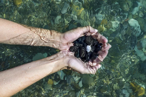 Руки с горсть камней море под водой — стоковое фото