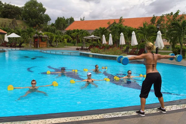 Аква аэробика фитнес-инструктор перед группой людей в воде, выполняя упражнения — стоковое фото
