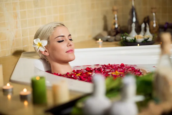 Женщина расслабляющая ванна с лепестками — стоковое фото