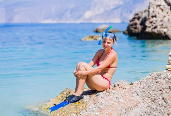 Женщина в подводным плаванием снастей, сидя на скалах — стоковое фото
