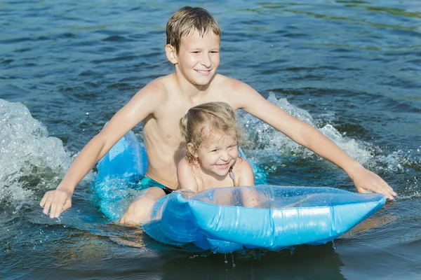 Братьев и сестер, веселятся во время летних морские купания с Робин яйцо синий мат воздушный бассейн Открытый — стоковое фото