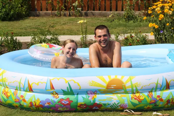 Молодая пара купается в надувной бассейн — стоковое фото