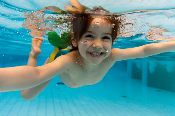 Девушка улыбается, плавание под водой в бассейне — стоковое фото