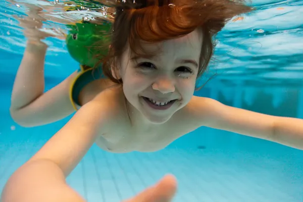 Девушка улыбается, плавание под водой в бассейне — стоковое фото